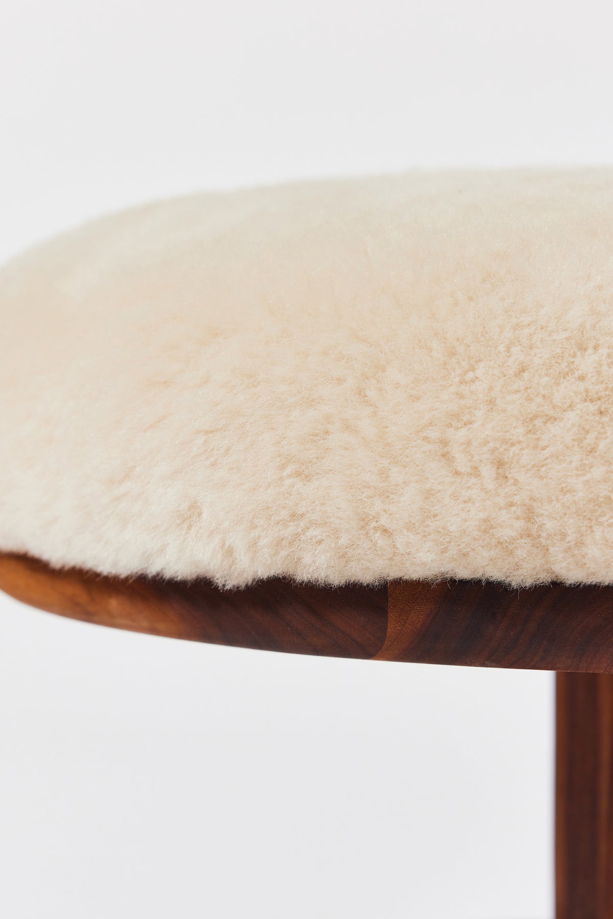 Muffin Man Tall stool in solid walnut with putty shearling seat, detail view 3. Handmade tall solid wood stool with shearling seat by Phillip's Daughter